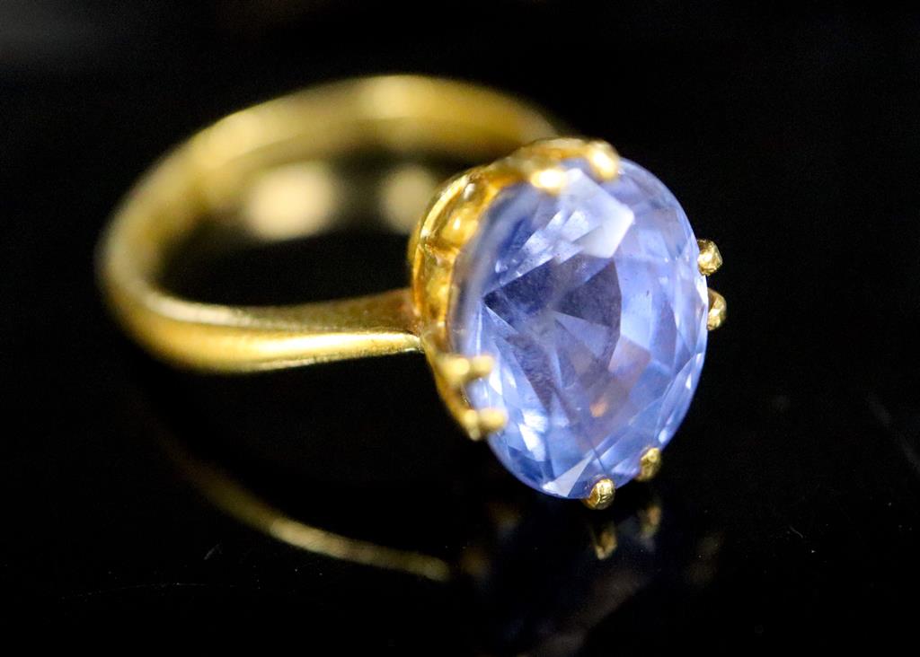 A gold (stamped 24k) and solitaire oval cut Ceylon sapphire set ring,